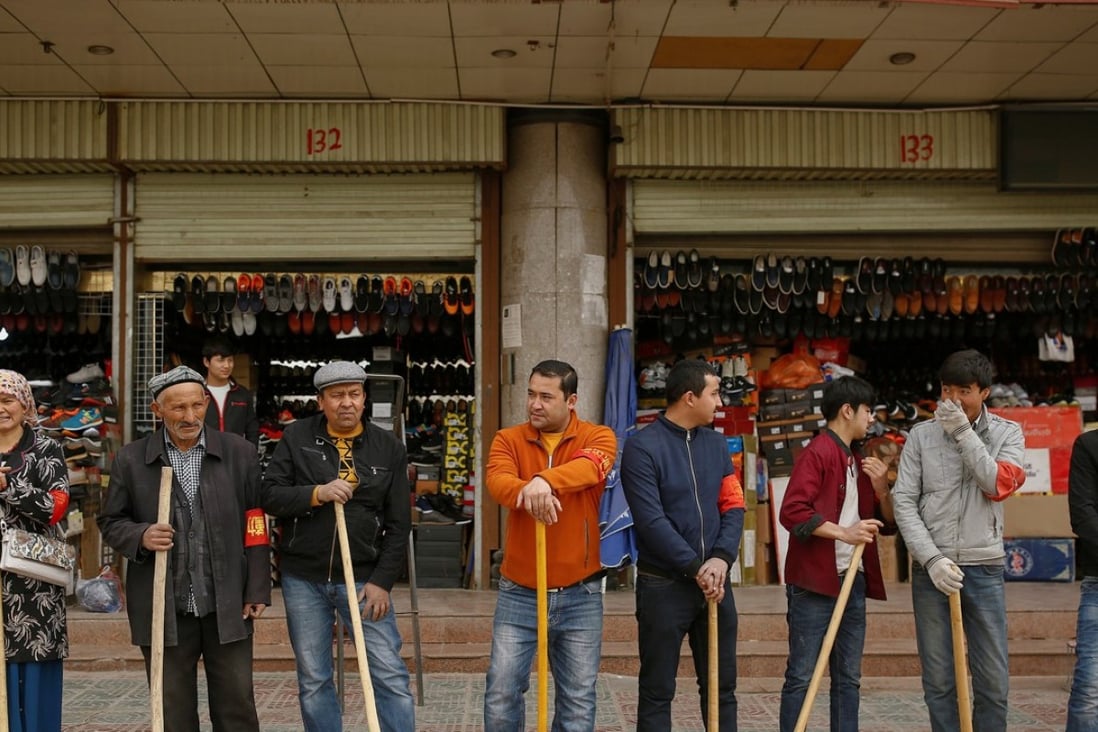 Shopkeepers line up with wooden clubs to perform their daily anti-terror drill outside the bazaar in Kashgar in Xinjiang. Photo: Reuters