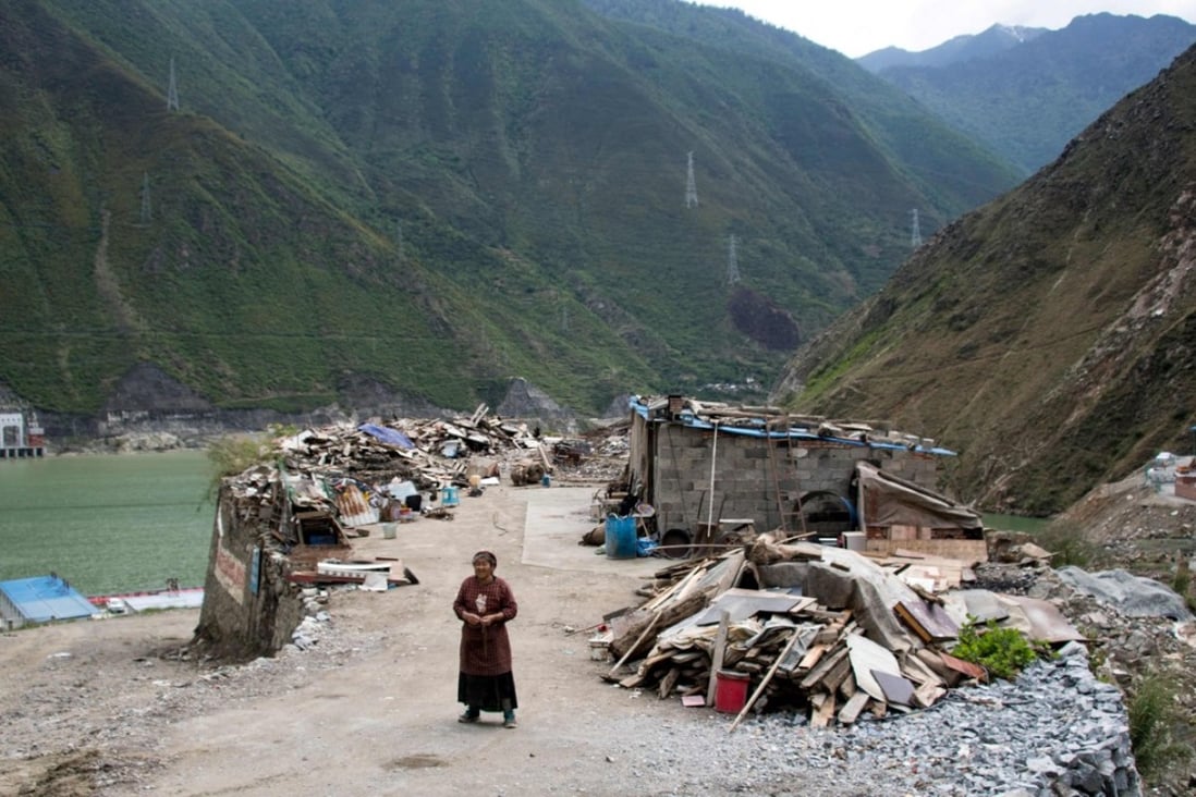 A woman stands next to the debris of demolished houses and her makeshift hut near Lianghekou in Sichuan province, the site of the latest huge dam to be built in China’s drive for greener sources of power. Photo: AFP