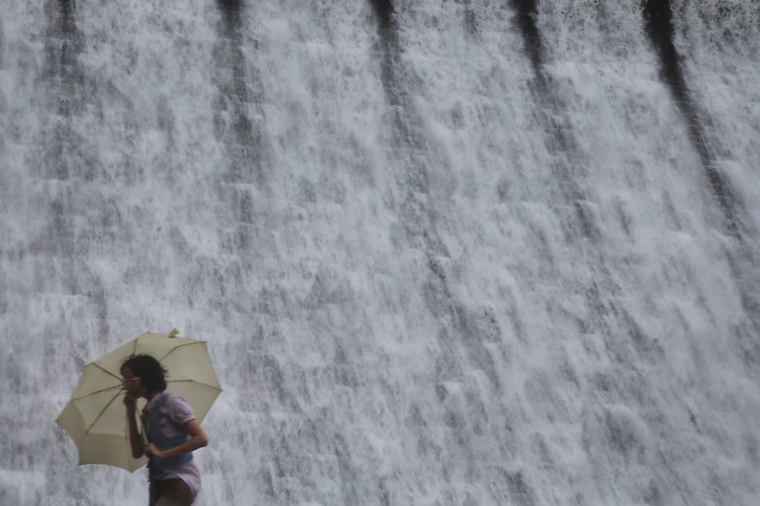 A woman walks past the Tai Tam Tuk Reservoir dam in the rain. For half a century now, the water Hong Kong harvests from rainfall has been insufficient to satisfy local demand. Photo: Sam Tsang