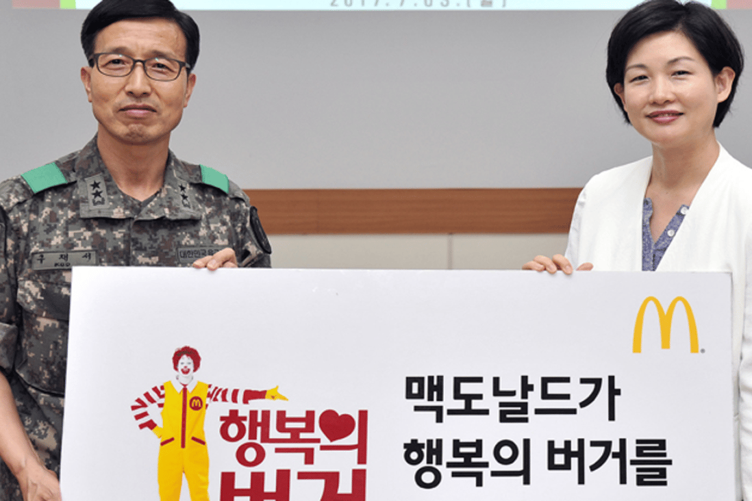 McDonald's Korea CEO Cho Ju-yeon, right, poses with Korea Army Training Center Commander Maj. Gen. Koo Jae-seo at the boot camp in Nonsan, South Chungcheong Province, Monday. The hamburger chain agreed to offer free burgers to recruits there. Photo: McDonald's Korea