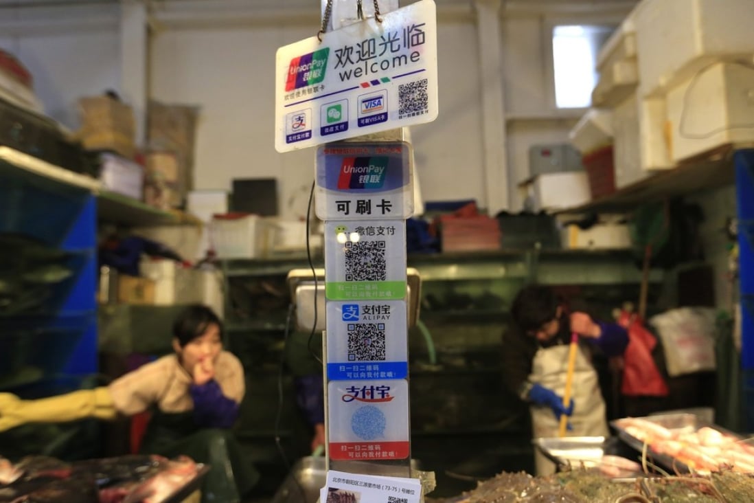 Signade at a Beijing seafood stall shows various non-cash payment methods for shopping, including Unionpay cards, and QR codes of Wechat and Alipay. Photo: EPA