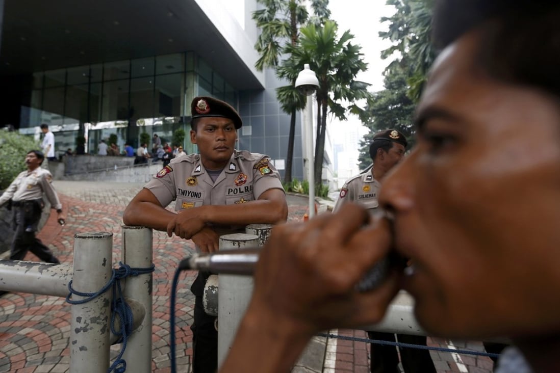 A policeman on guard as a protester shouts slogans outside the Corruption Eradication Commission building in Jakarta. Photo: Reuters