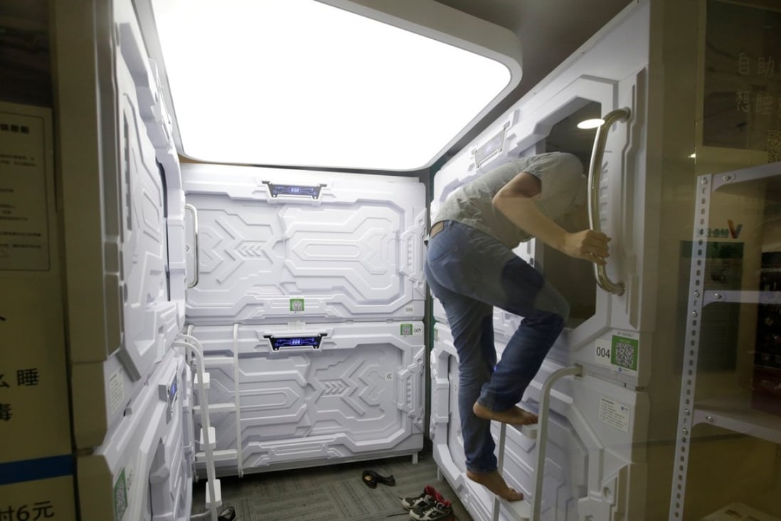 A man climbs up a ladder as he prepares to sleep in a capsule bed unit at Xiangshui Space during a lunch break in Beijing's Zhongguancun area. Photo: Reuters
