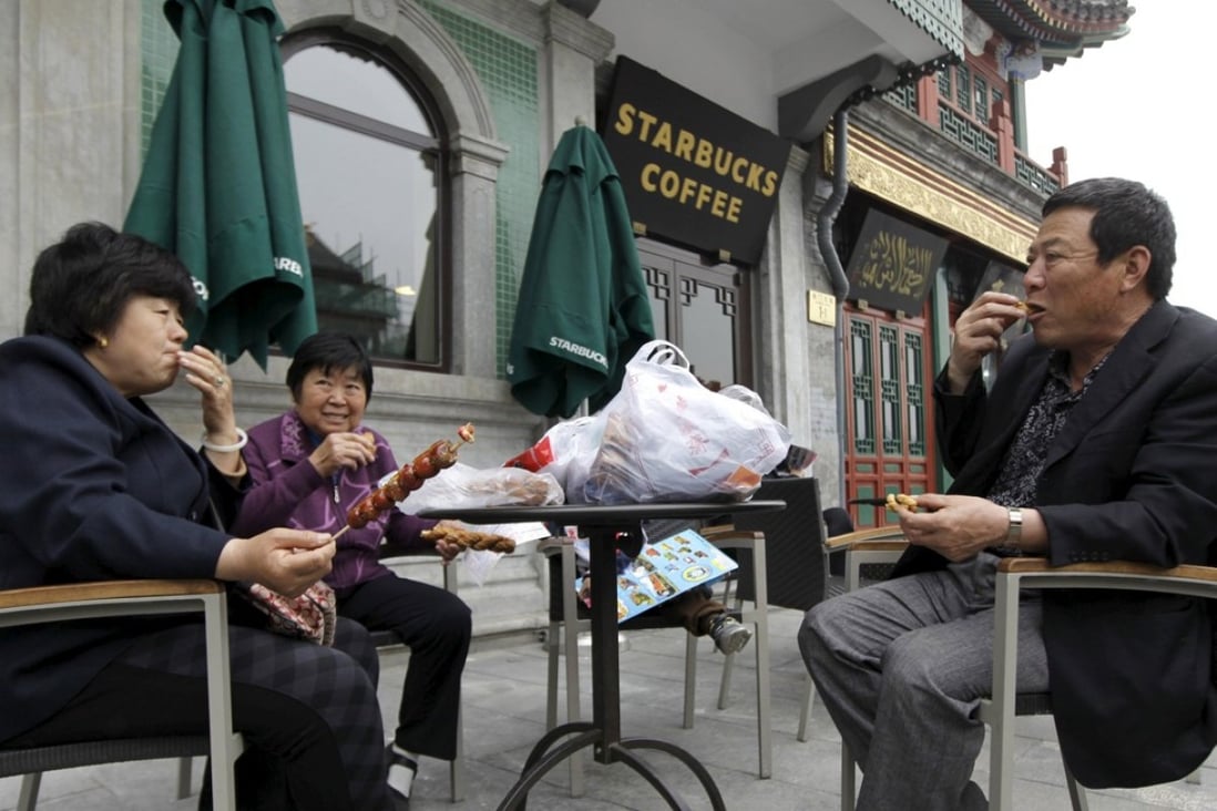 People eat snacks in a yard of a Starbucks coffee store at Qianmen Commercial Street in central Beijing. Photo: Reuters