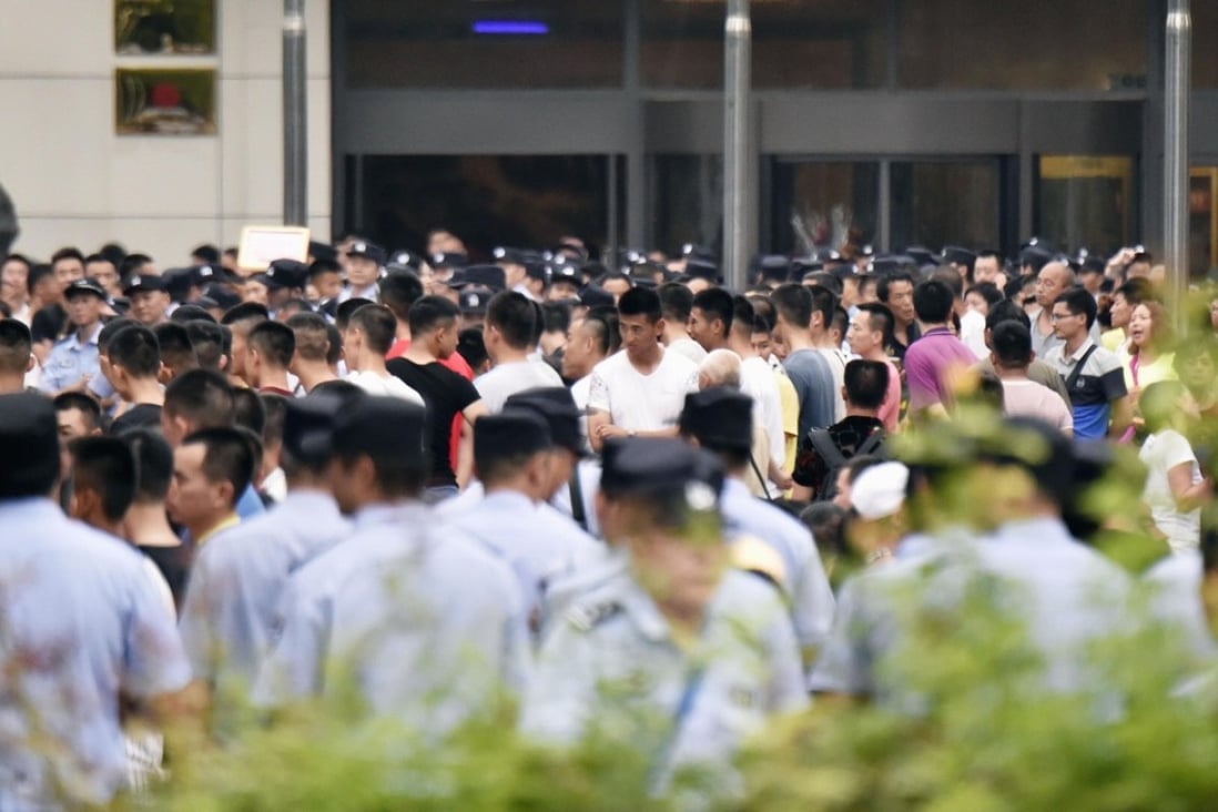 Police keep a close eye on a crowd of people protesting against an investigation into an alleged pyramid scheme on July 24. Photo: Kyodo