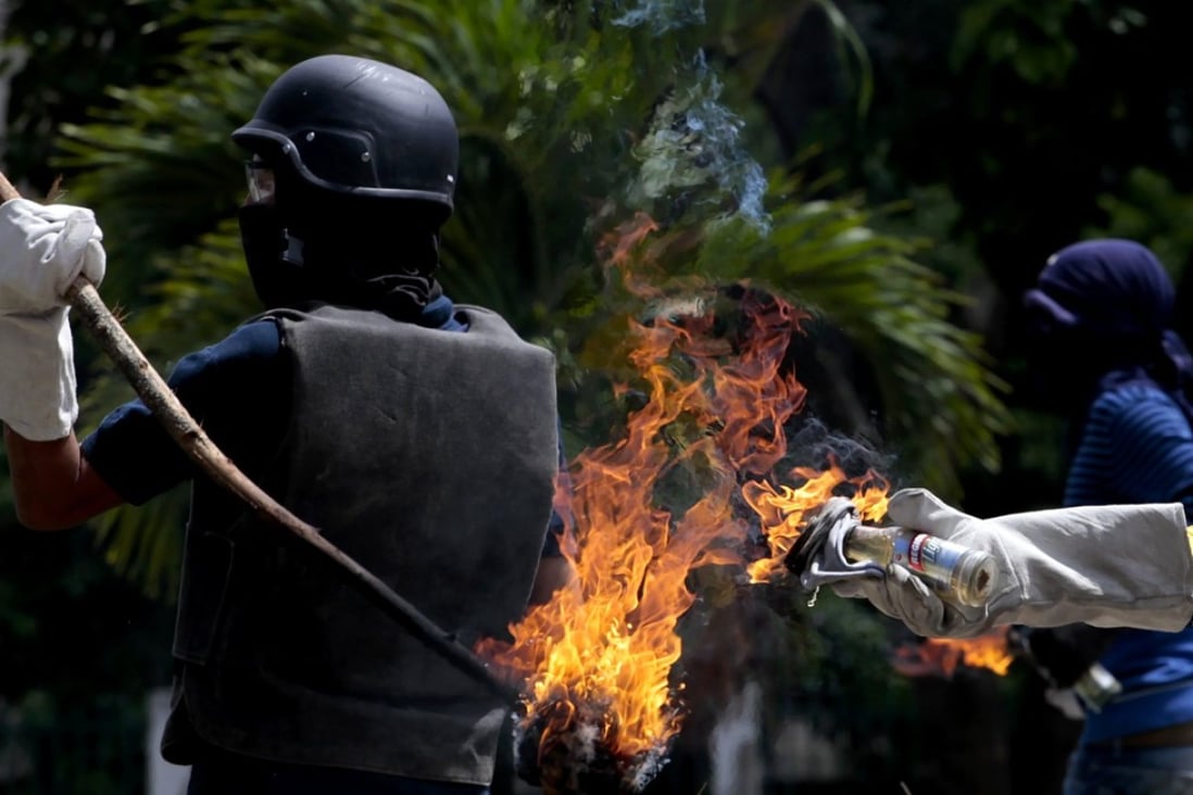 Opposition protesters clash with Bolivarian National Guard while blocking a street in during a protest against elections for the National Constituent Assembly in Barquisimeto, Venezuela, on Sunday. Photo: EPA