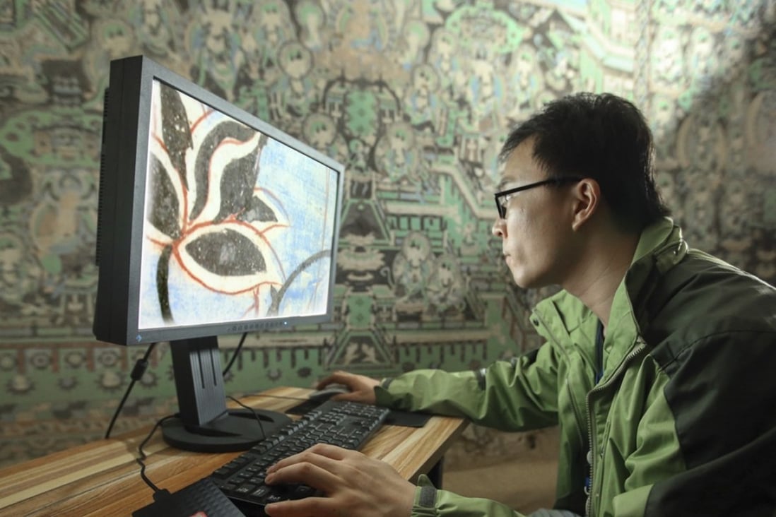 A staff member from the Dunhuang Research Academy performs digitalisation work in one of the Mogao caves. Photo: Dunhuang Research Academy