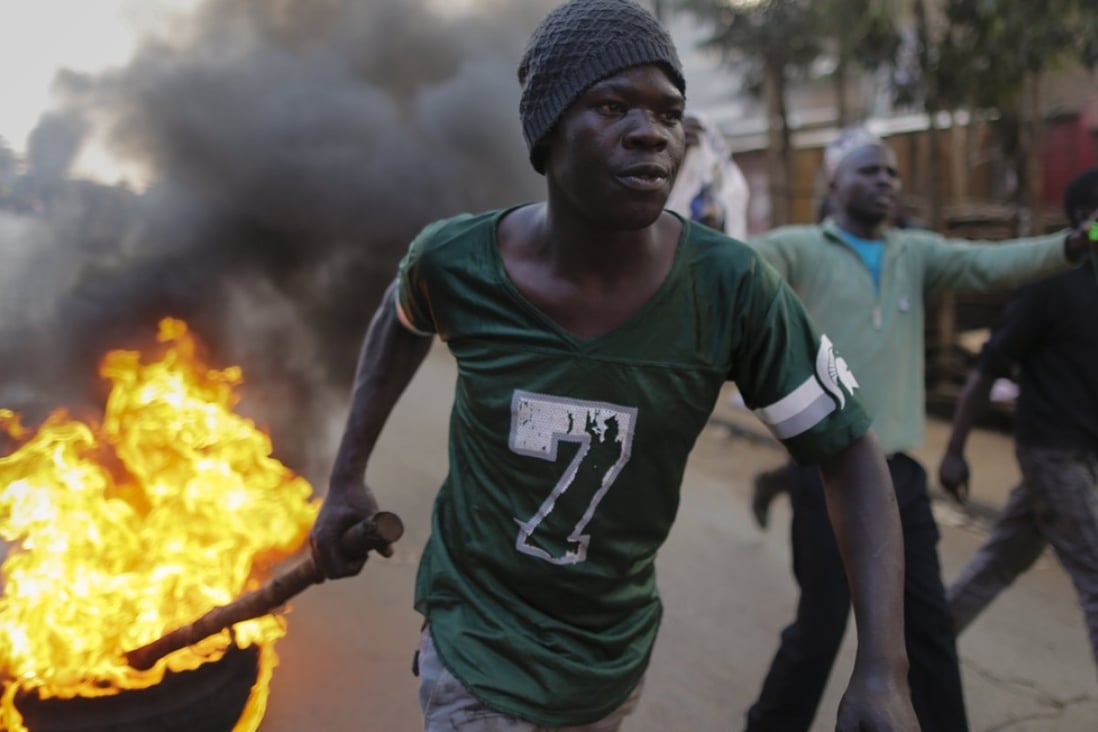 A supporter of the opposition leader Raila Odinga drags a burning tyre down the street during a protest in Kibera slum, one of Odinga's strongholds in Nairobi, Kenya, on Wednesday. Photo: EPA