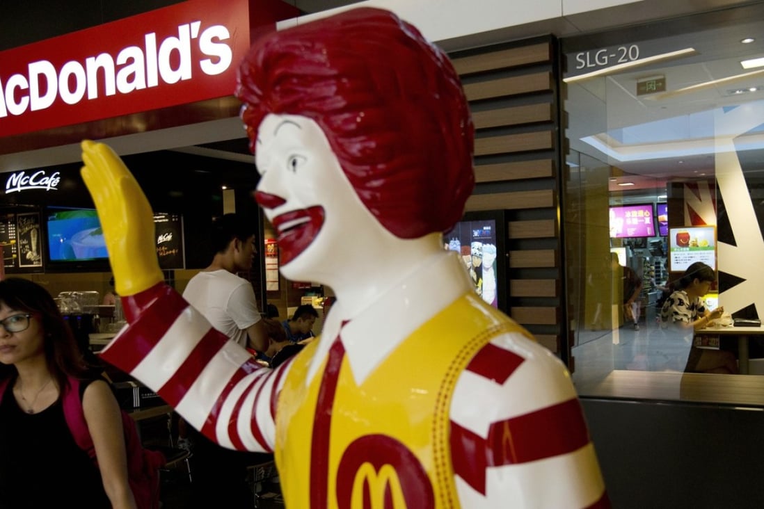 A customer walks past a statue of Ronald McDonald outside a McDonald's restaurant in Beijing. The fast food giant is targeting smaller mainland Chinese cities as part of a five year expansion plan. Photo: AP