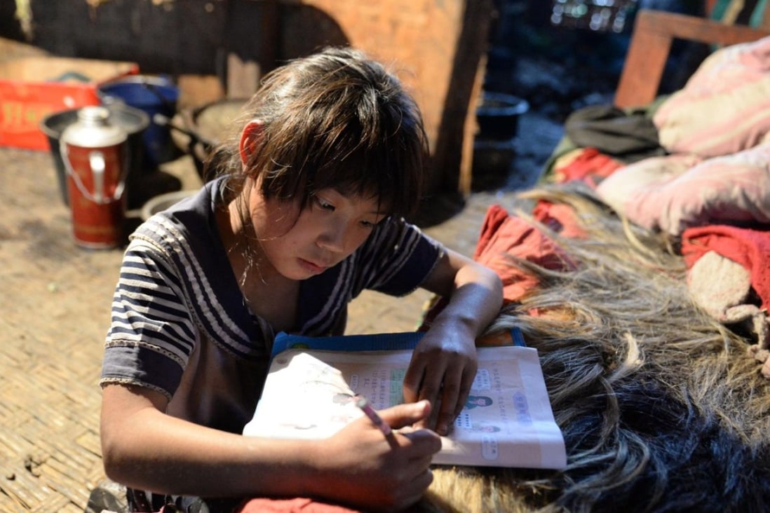 A file picture of a girl in a mountainous area of Yunnan province doing her school homework on her bed in Mukeji village. Photo: Xinhua