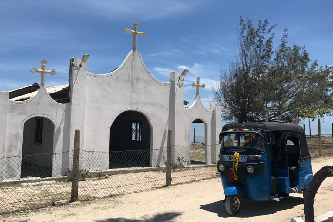 A three-wheeler passes in front of a Catholic church in Nainativu. Photo: Paul Niel