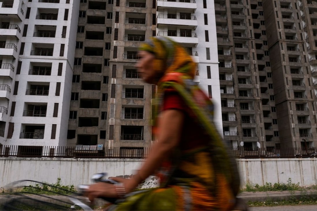 An Indian cyclist rides past incomplete residential flats in Greater Noida, southeast of New Delhi. Real estate accounts for about US$19.5 billion of stressed loans in India. Photo: AFP