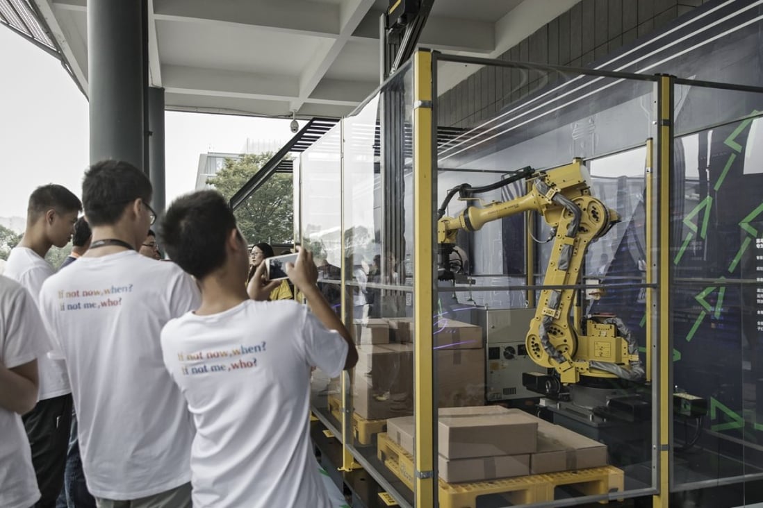 Employees and visitors take photographs of logistic and parcel delivery robots on display at the Alibaba Group headquarters in Hangzhou, China, on Friday, Sept. 8, 2017. Photo: Bloomberg