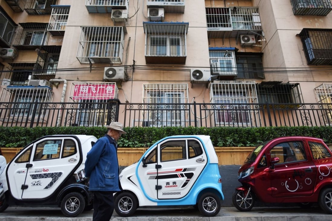 A man walks past electric cars parked on a pavement in Beijing. Photo: AFP