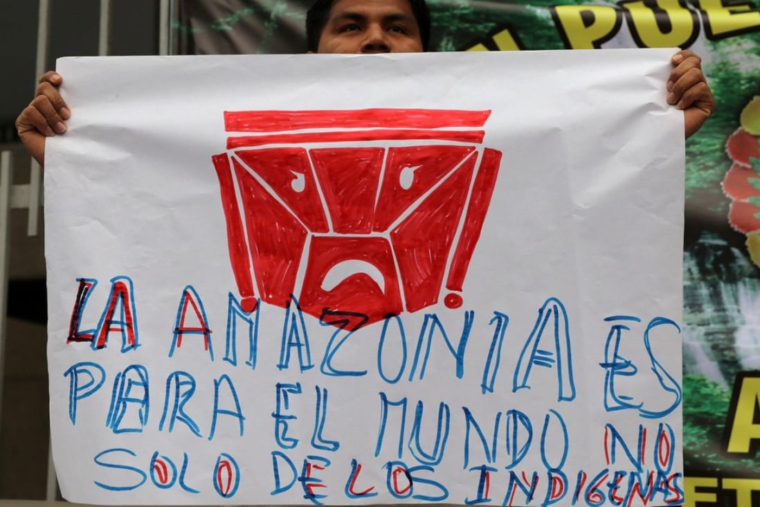 A protester holds a sign that reads “The Amazon is for the world, not only for the indigenous”. Photo: Reuters
