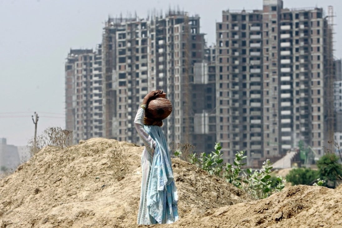 A village woman carries potted water as she walks in front of a backdrop of under construction high rise housing in Gurgaon, a suburb south of New Delh. Photo: AP