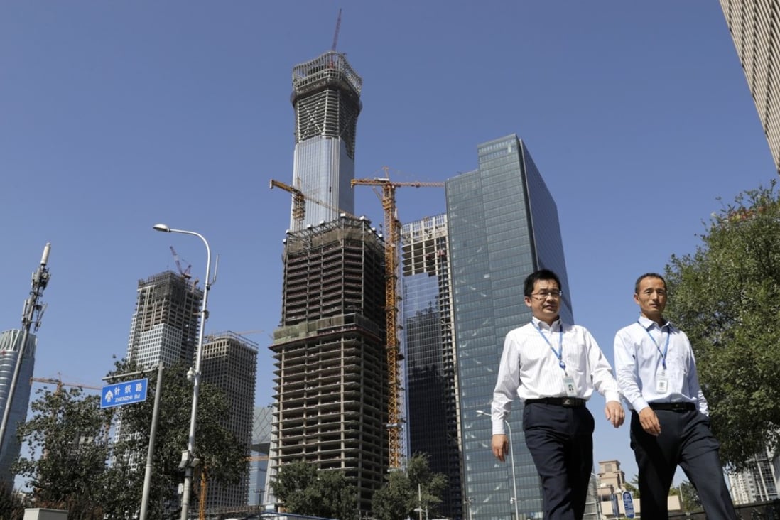 Chinese people walk by a construction site at the Central Business District in Beijing. By downplaying hard economic targets, future growth will slow down but be more balanced and sustainable. Photo: AP