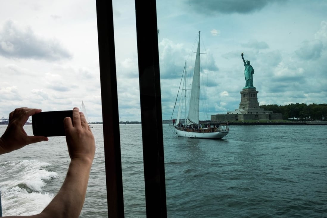 A Liberty Island ferry passenger tries to capture the Statue of Liberty, linked in the popular psyche with arriving immigrants, in New York City in August. Photo: AFP