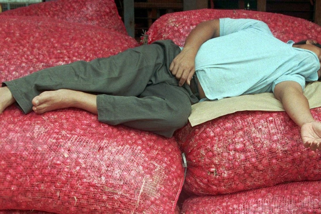 An exhausted onion trader catches forty winks on top of piles of his merchandise. Photo: Reuters