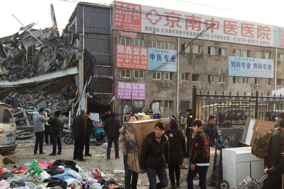 Residents who survived the fatal fire in Daxing carry their belongings out of the ruins. Photo: AFP