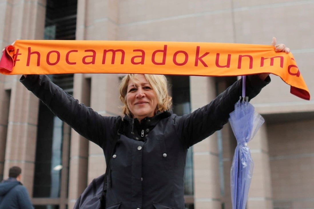 A demonstrator holds a scarf reading “Do not touch my academics” in front of the Justice Palace. Photo: Reuters