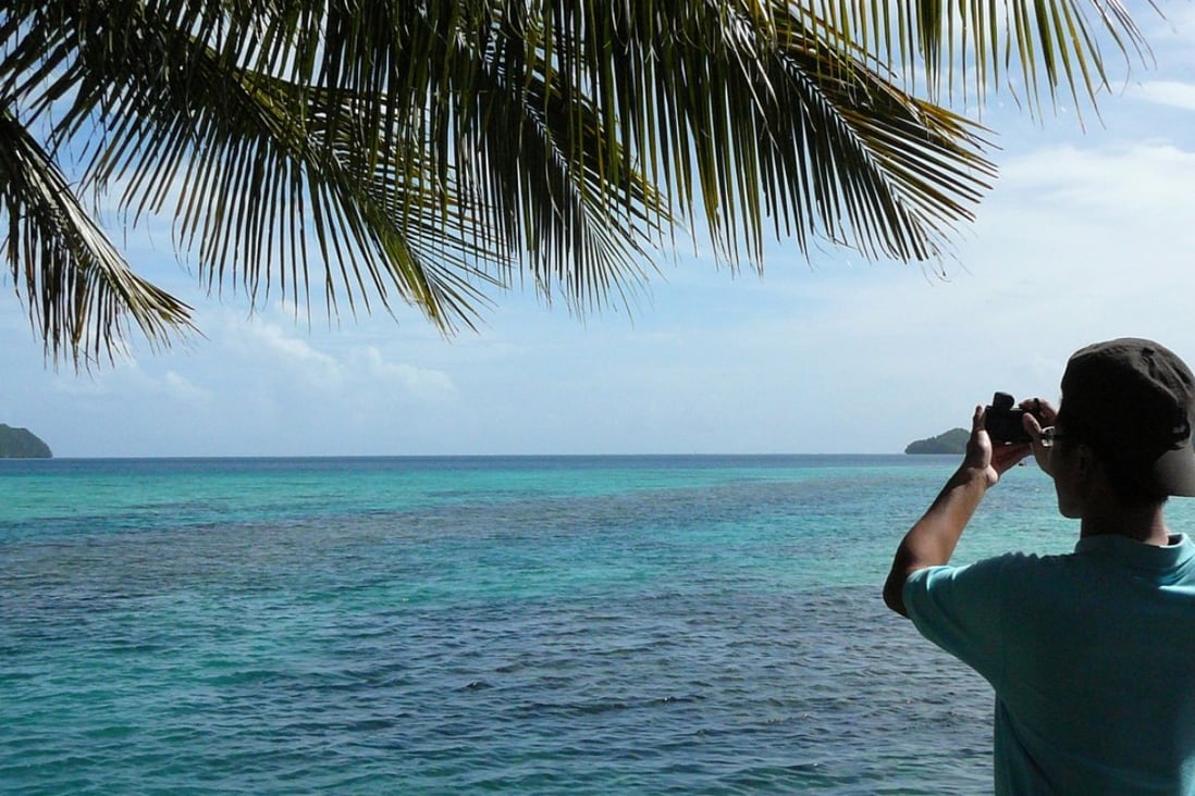 File photo of a tourist taking a photograph of the sea in Palau. Photo: EPA