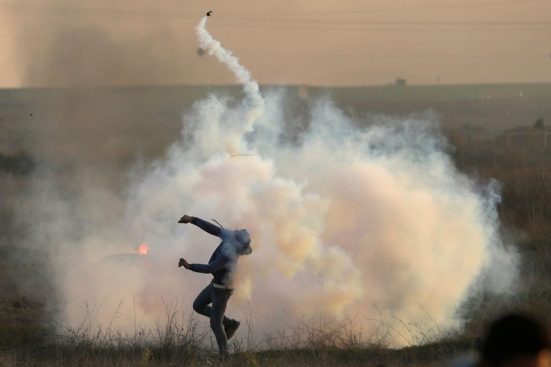 A Palestinian protester throws a tear gas canister back at Israeli forces during clashes near the Israel-Gaza border. Photo: AFP