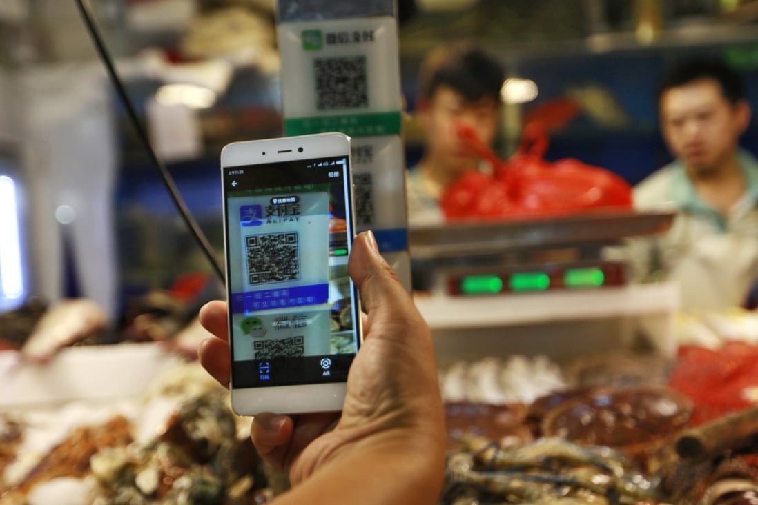 A customer scans an Alipay QR code to make a payment via a mobile phone in a market in Beijing. Photo: EPA