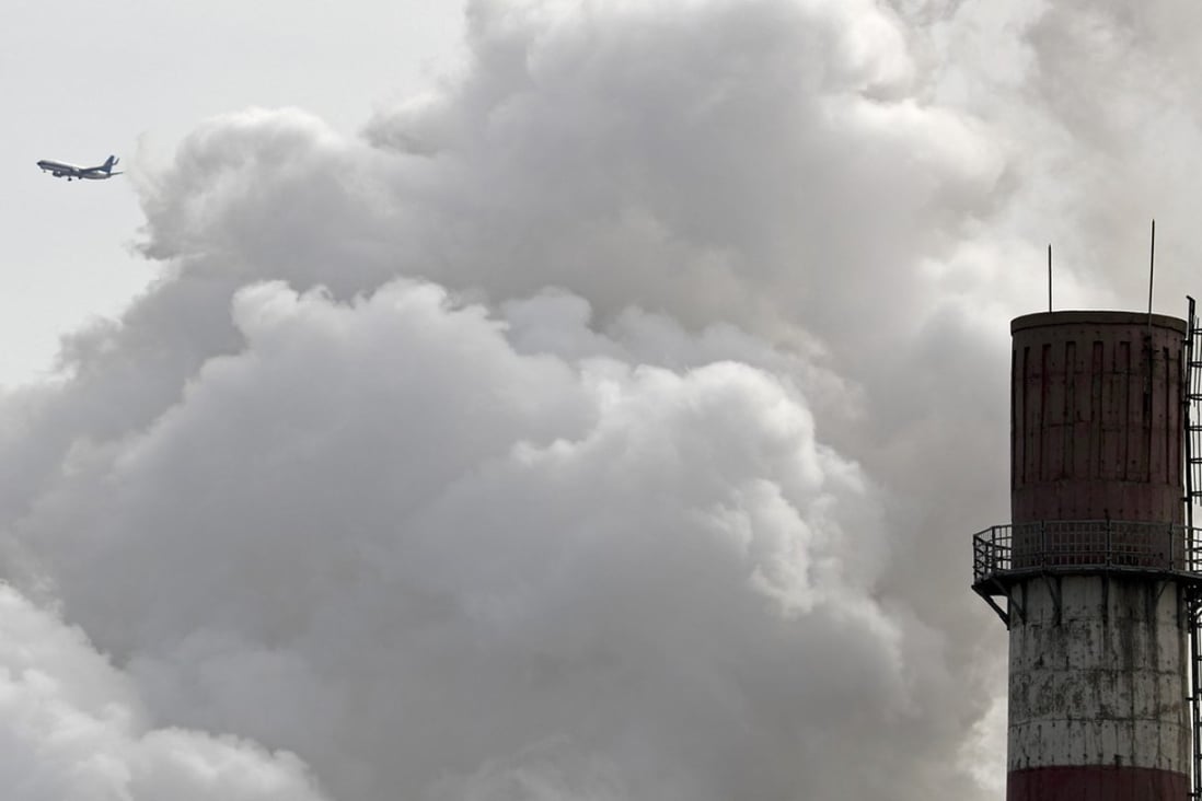 A plane flies past clouds of smoke billowing from a coal-fired power plant in Beijing. China on Tuesday launched a nationwide carbon-trading scheme, solidifying its role as an emerging leader in the fight against climate change. Photo: AP
