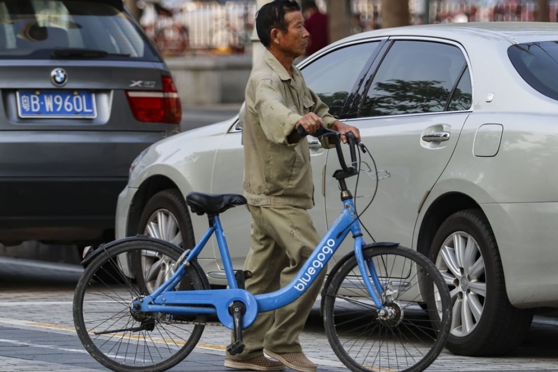 A man is seen dragging a Bluegogo bike-sharing bicycle in Shenzhen’s Futian district on October 24, 2017. Photo: Roy Issa