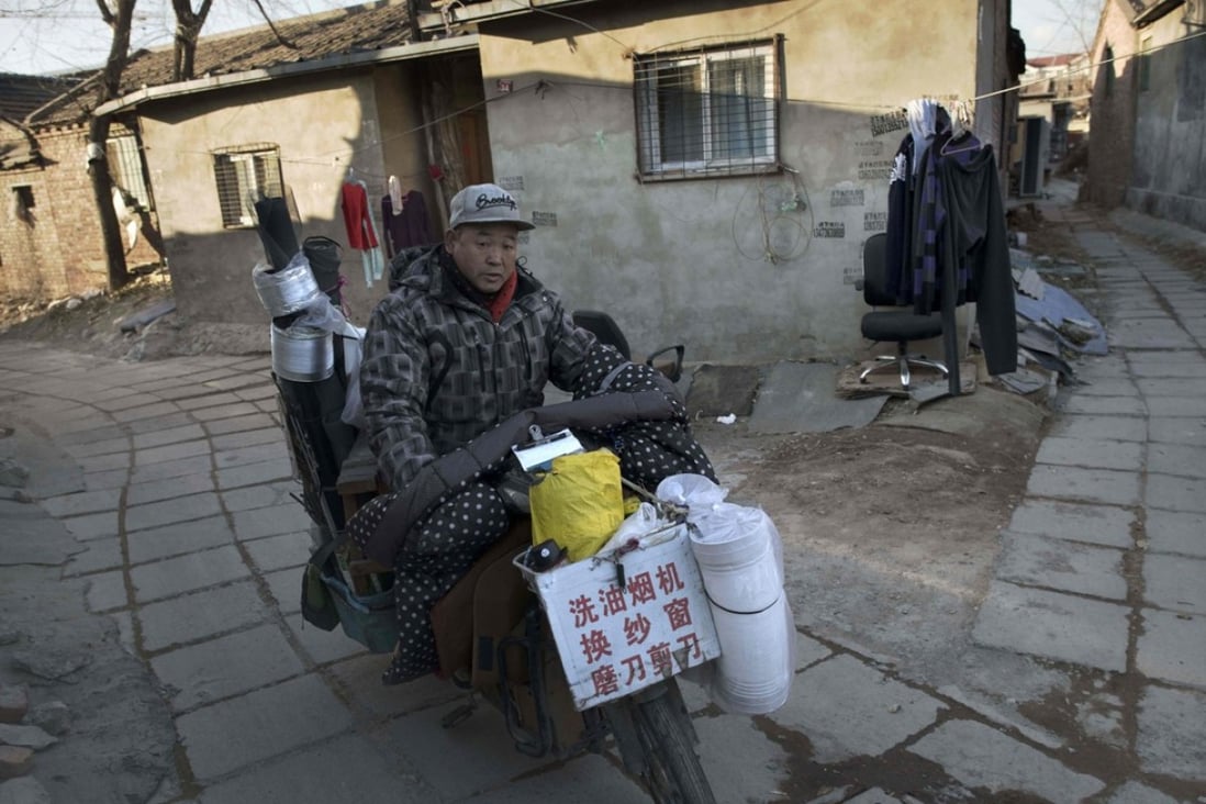 A cooker hood cleaner rides his bike through a migrant village on the outskirts of Beijing. Photo: AFP