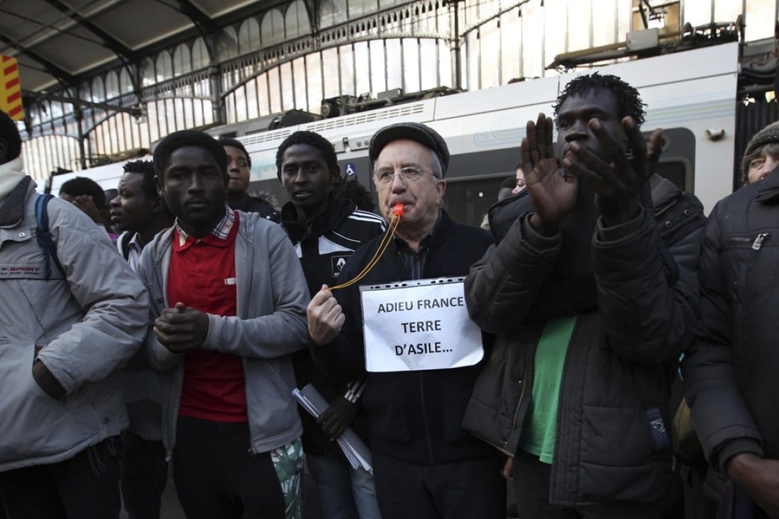 A demonstrator with a placard reading “Goodbye France, land of asylum” supports migrants from Sudan at the Bayonne train station, southwestern France, on December 19. Photo: AP