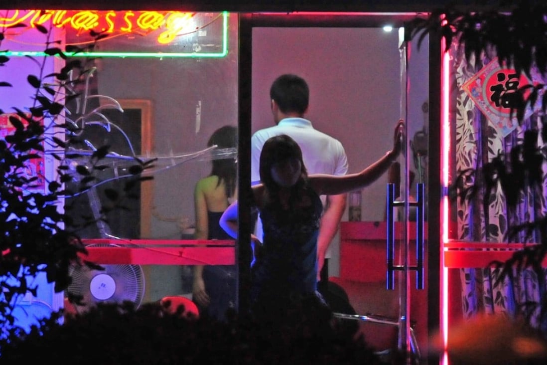 A woman awaits customers from the doorway of a neon-lit barber shop in Beijing in 2008. Sex workers ply their trade in bars, massage spas, karaoke parlours and the barber shops that are found in many Beijing back alleys. Photo: AFP