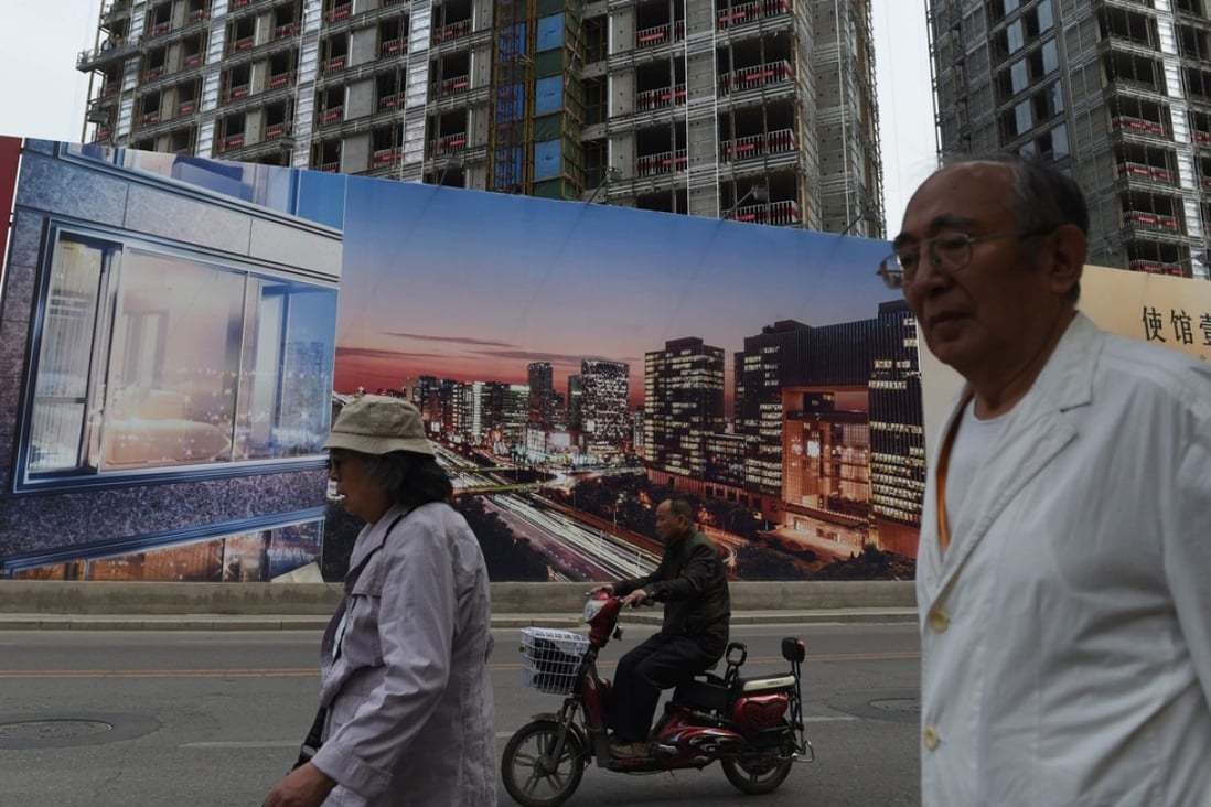 People walk past a hoarding advertising a new housing project in Beijing. China’s banking regulator has expressed the need to control rising household debt levels, much of which is attributable to mortgage loans. Photo: AFP