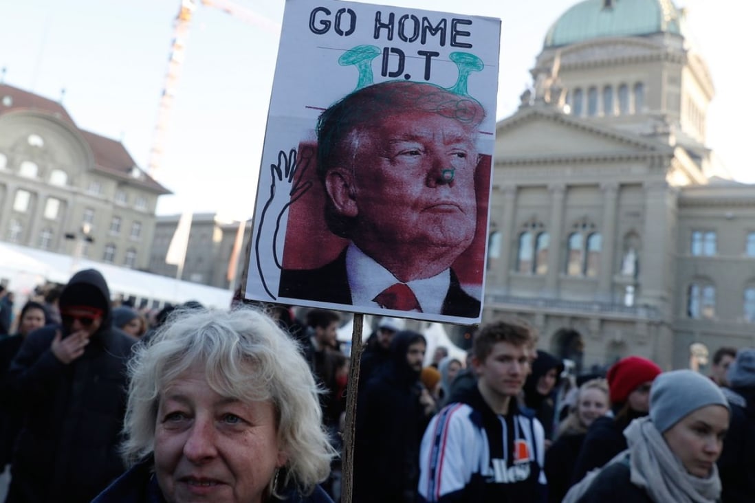 A woman holds a sign with a portrait of US President Donald Trump during a protest in Bern against his planned visit to the World Economic Forum. Photo: AFP