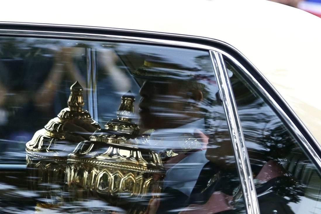 Thai King Maha Vajiralongkorn Bodindradebayavarangkun (L) and Thai Princess Maha Chakri Sirindhorn with the royal relics and ashes of the late Thai King Bhumibol Adulyadej sit in a car during the procession for the transferring of the relics and ashes to be enshrined in Wat Rajabopidh Sathitmahasimaram and Wat Bovoranives Vihara temples, as part of the royal cremation ceremony, at the Grand Palace in Bangkok, Thailand, on October 29, 2017. A Thai student fled after being charged under a law of insulting the king. Photo: EPA-EFE