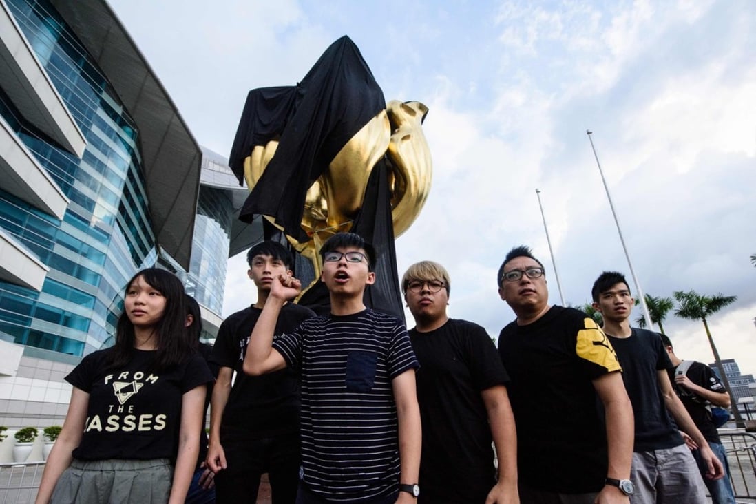 Demosisto party members, including Agnes Chow (left) and Joshua Wong (centre), shout slogans after covering the Golden Bauhinia statue with a black cloth last June, ahead of the 20th anniversary of the city's handover from Britain to China on July 1. Photo: AFP