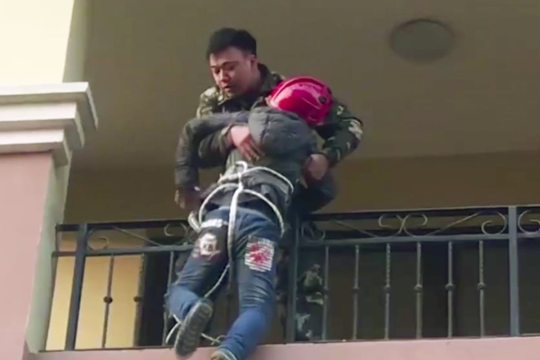 A firefighter rescues a 10-year-old from a balcony in eastern China after he was lowered on to it by his grandmother to retrieve a fallen quilt. Photo: News.163.com