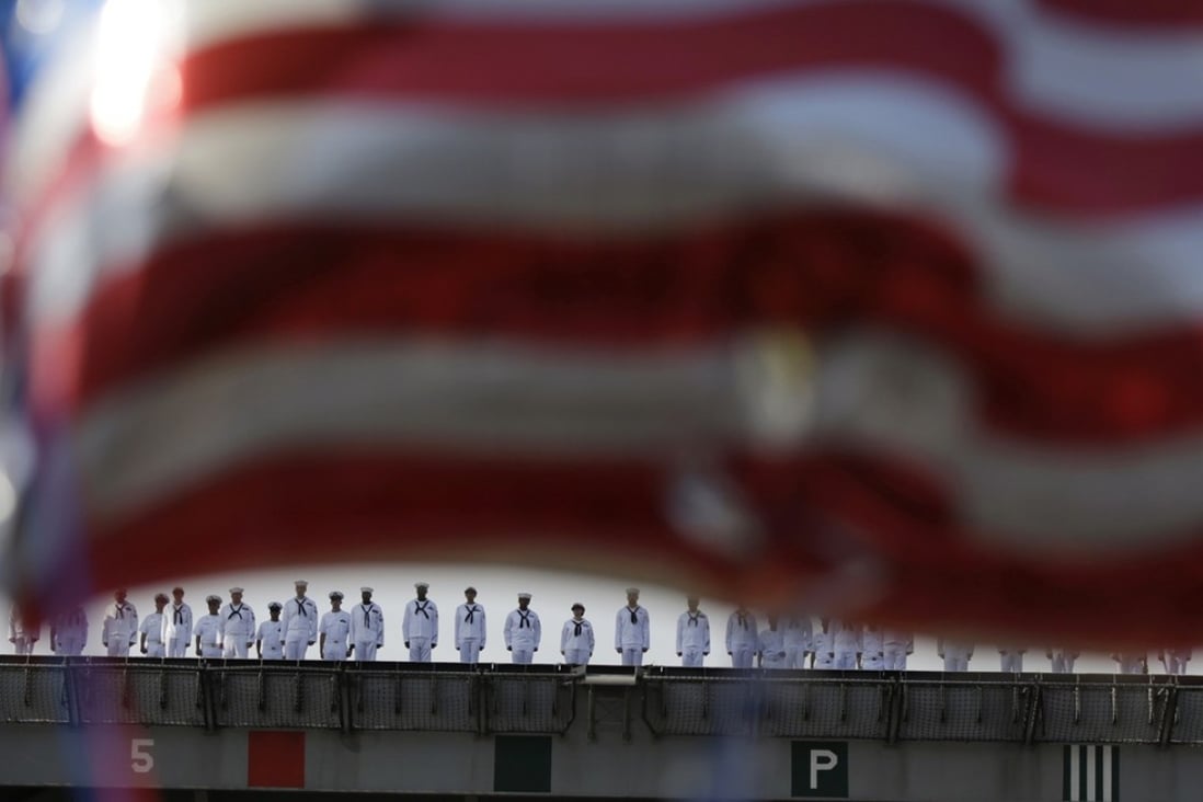 FILE - In this Oct. 1, 2015 file photo, sailors of U.S. navy nuclear-powered aircraft carrier USS Ronald Reagan man the rails upon arrival as some U.S. flag-shaped balloons are hoisted to welcome them at the U.S. Navy's Yokosuka base in Yokosuka, south of Tokyo. Donald Trump has raised the specter of withdrawing U.S. forces from South Korea and Japan unless they share more of the burden of hosting the 80,000 troops, even as neighboring North Korea has conducted nuclear and missile tests with unprecedented intensity. (AP Photo/Eugene Hoshiko, File)