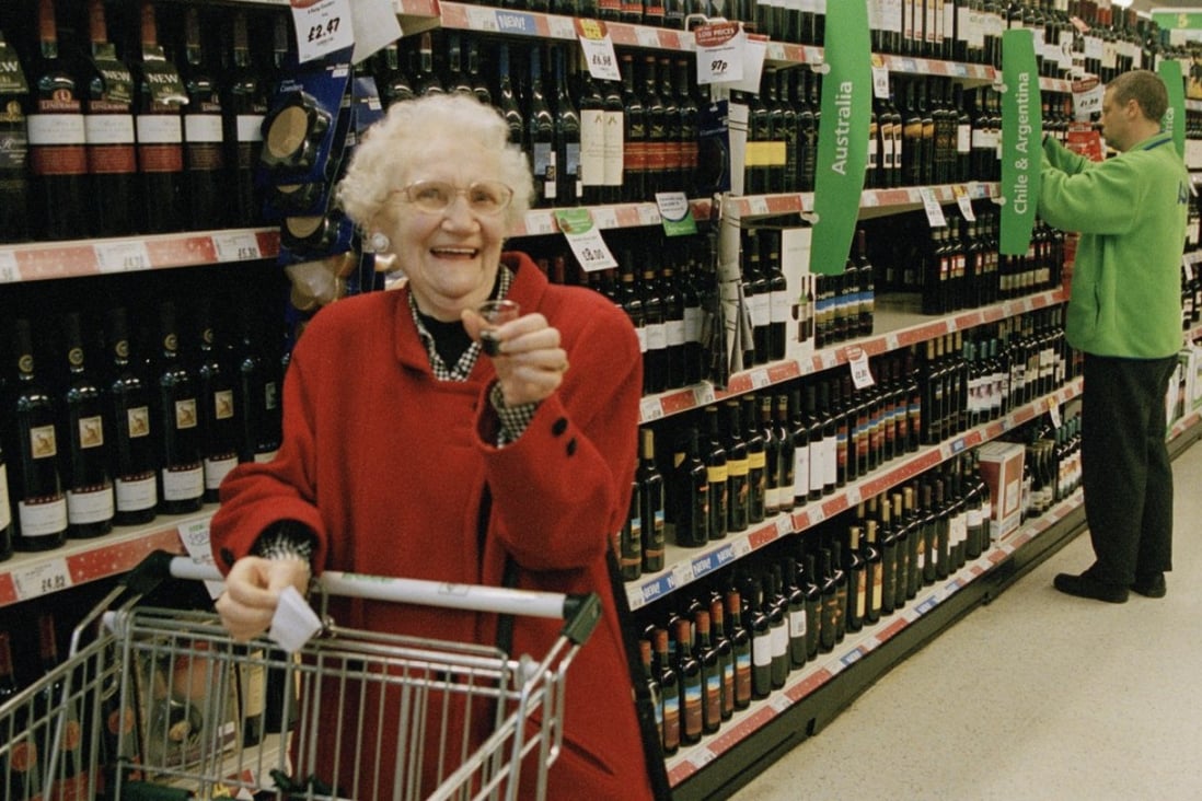 An elderly shopper enjoys a small glass of complementary red wine, as she shops in the drinks aisle of an Asda supermarket in Britain, in this file photo. Photo: Gideon Mendel / Corbis