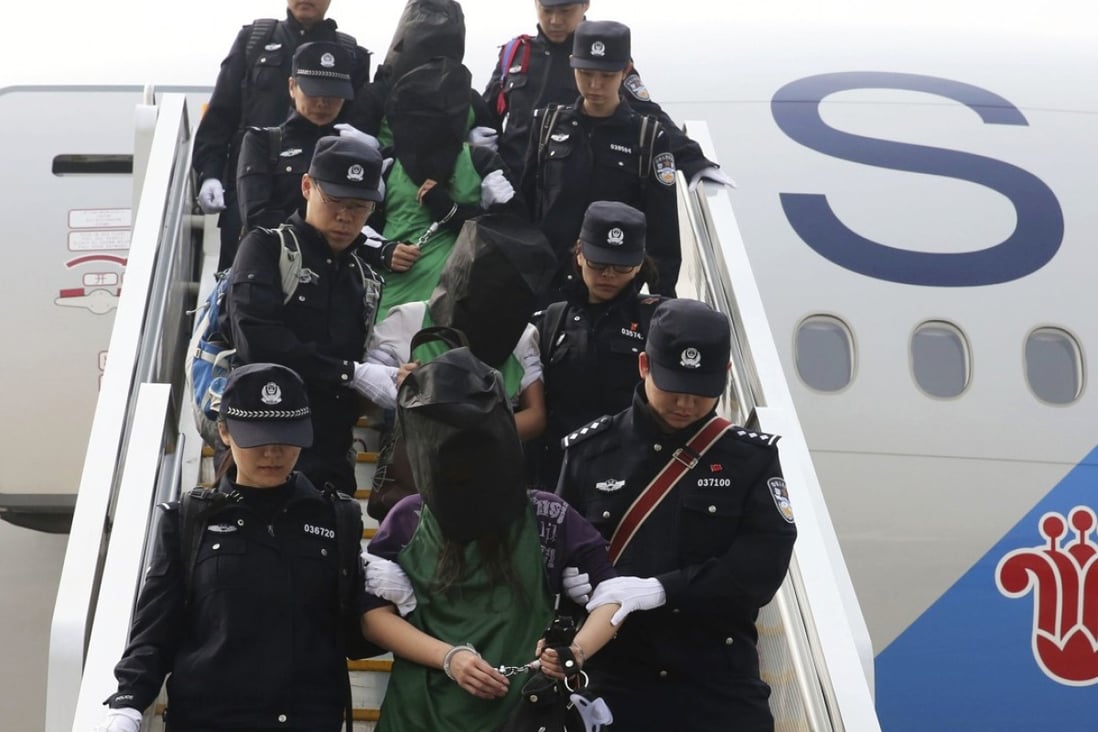 Extradited mainland Chinese and Taiwanese suspects involved in wire fraud are escorted off a plane at Beijing international airport in April 2016. Photo: Associated Press