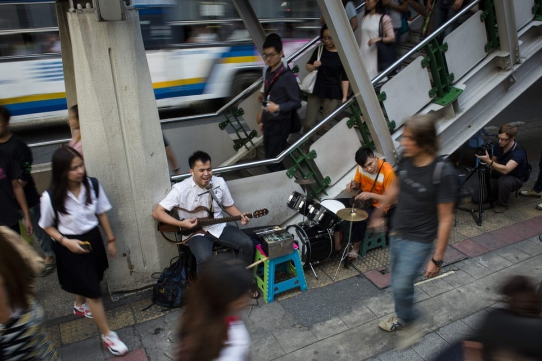 Singhkum Boonriang, 28, performs with his guitar in front of a Skytrain station in Bangkok. He's one of hundreds of blind singers who perform across the Thai capital. Photo: AFP