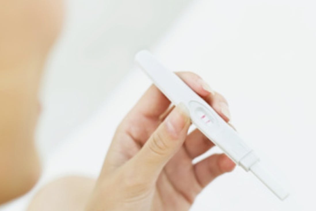 young woman looking at a pregnancy test kit