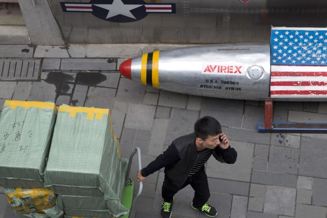 A delivery man calls for directions while pulling a cart of goods past a US apparel store in Beijing on Friday. China is in a spiralling trade dispute with the United States. Photo: AP