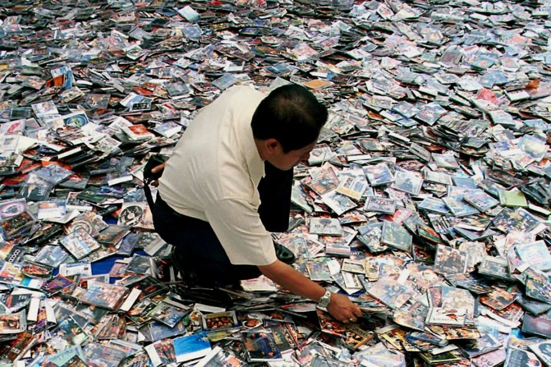 A City Hall worker spreads million of the pirated video compact disc (VCDs), software and CDs on the floor before destroying them in Kuala Lumpur. Photo: AP/Teh Eng Koon