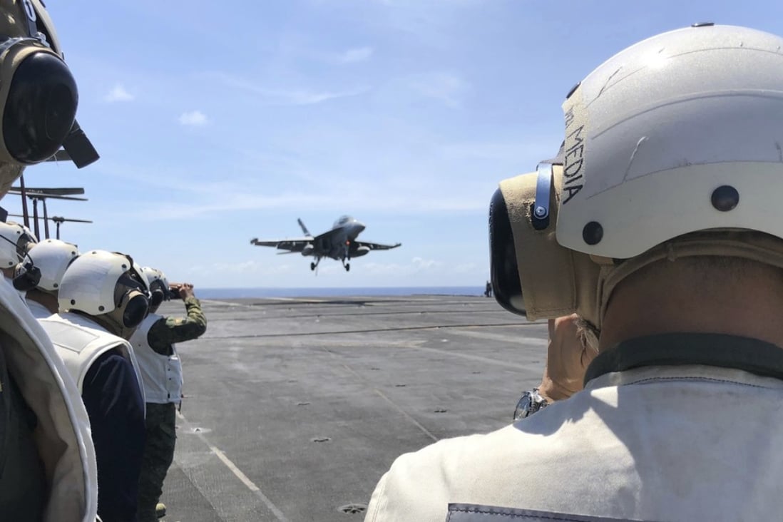 Philippine generals and journalists watch from the deck of the US aircraft carrier Theodore Roosevelt as a US fighter jet lands on Tuesday, in international waters off South China Sea. Photo: AP 