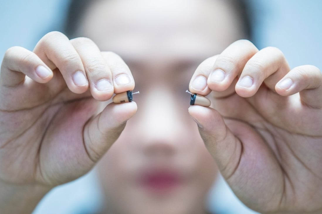 A woman in China holds a pair of skin-coloured earpieces. Similar devices were used in the Singapore exam cheating plot. File photo: Reuters