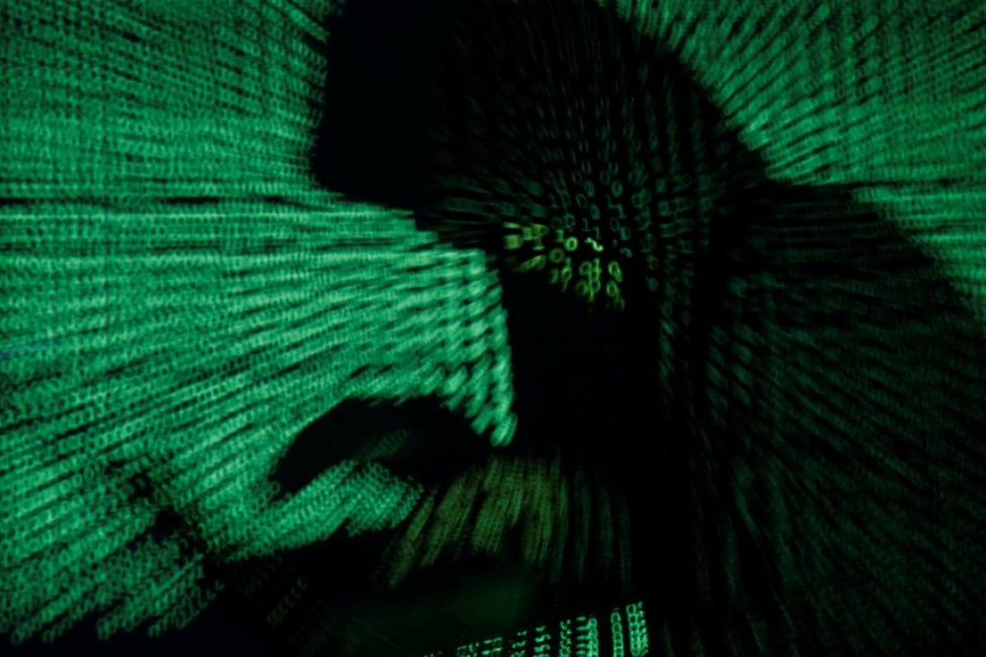 A hooded man holds a laptop computer as cyber code is projected on him in this illustration picture taken on May 13, 2017. Photo: Reuters