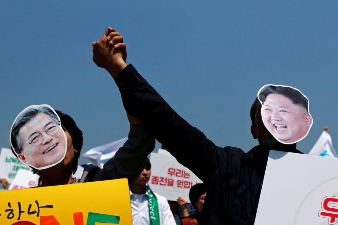 People attending a pro-unification rally in Seoul hold hands as they wear masks of South Korea President Moon Jae-in and North Korean leader Kim Jong-un. Photo: Reuters