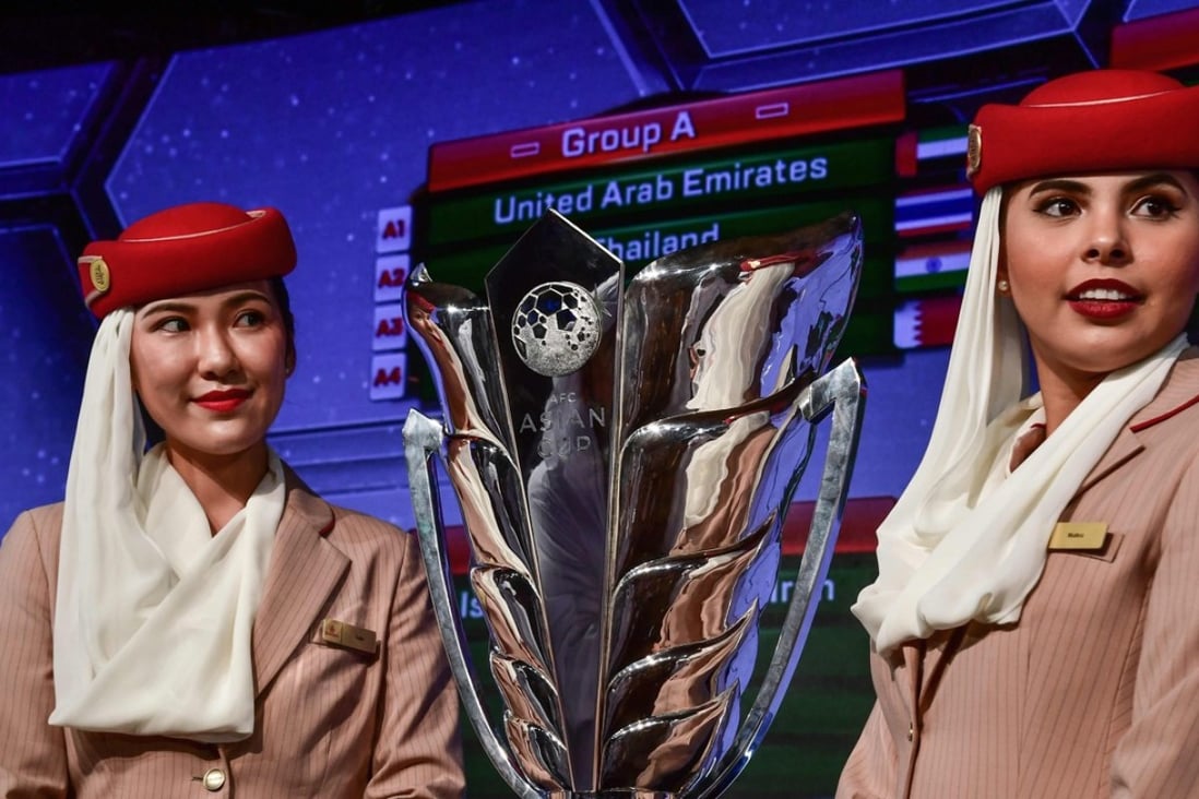 Two Emirates Airlines air hostesses pose next to the AFC Asian Cup trophy during the draw in Dubai. Photos: AFP